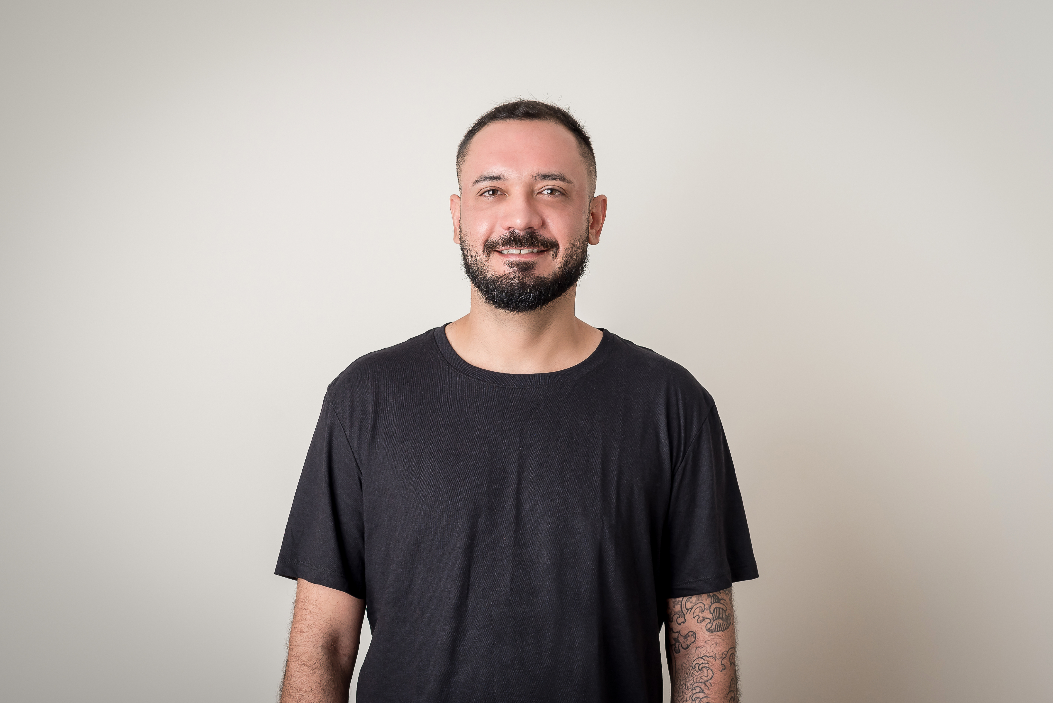Portrait of a man with brown hair and glasses on a flat gray background.